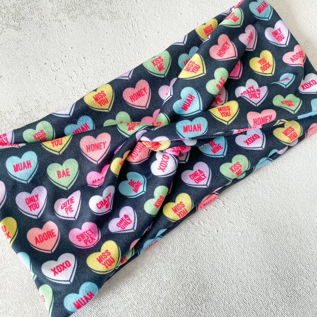 Wide fabric headband.  Black with colorful conversation hearts.  